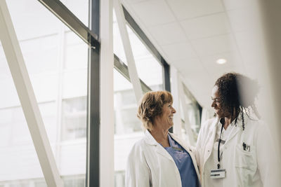 Happy multiracial female physicians looking at each other in hospital