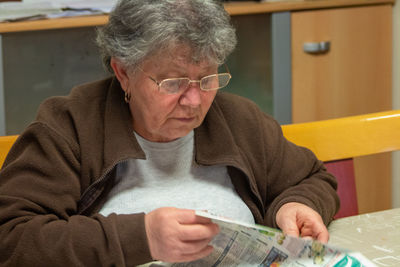 Close-up of senior woman in eyeglasses reading newspaper