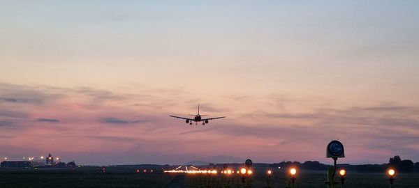 Low angle view of airplane flying against sky during sunset