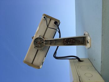 Low angle view of telephone pole against clear blue sky