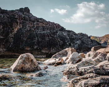 Rock formations in sea against sky