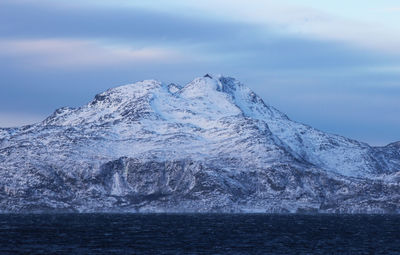 Scenic view of sea by mountain against sky