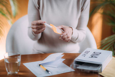 Midsection of woman putting dna sample in envelope