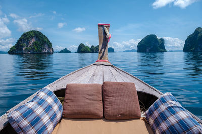 Rear view of woman sitting on boat on sea against sky