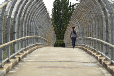 Rear view of woman walking on footbridge