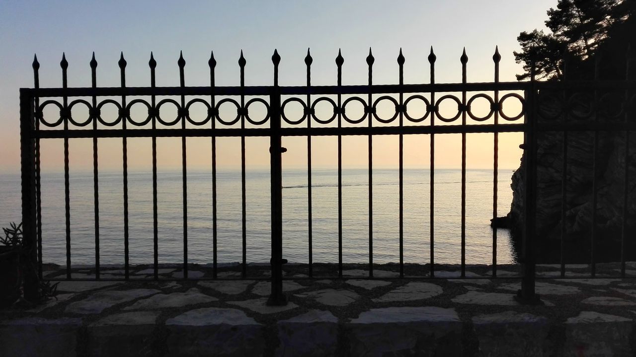 SILHOUETTE FENCE BY RAILING AGAINST SKY