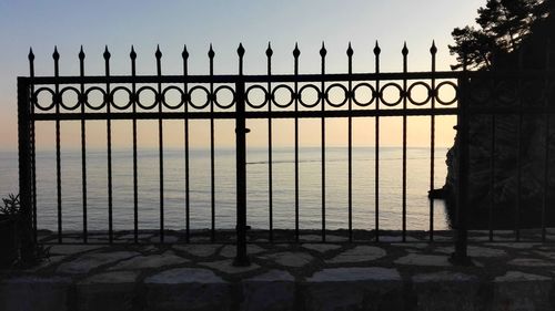 Silhouette fence by building against sky