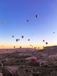 Hot air balloons flying over land during sunset