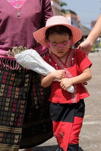 Girl with bouquet walking by mother on road