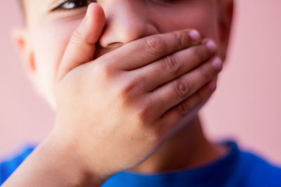Close-up portrait of boy with hand covering mouth