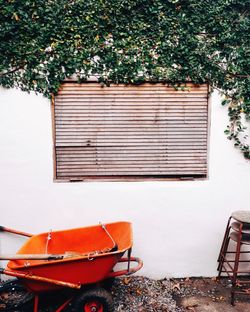 Orange wheelbarrow against wall