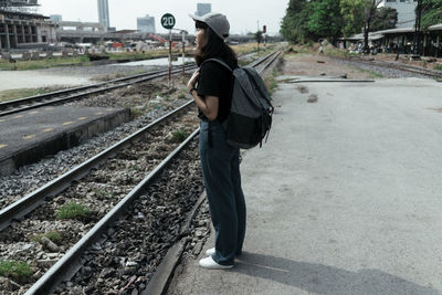 Side view of woman standing on railroad tracks