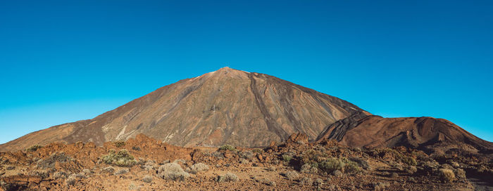 Scenic view of arid landscape against clear blue sky