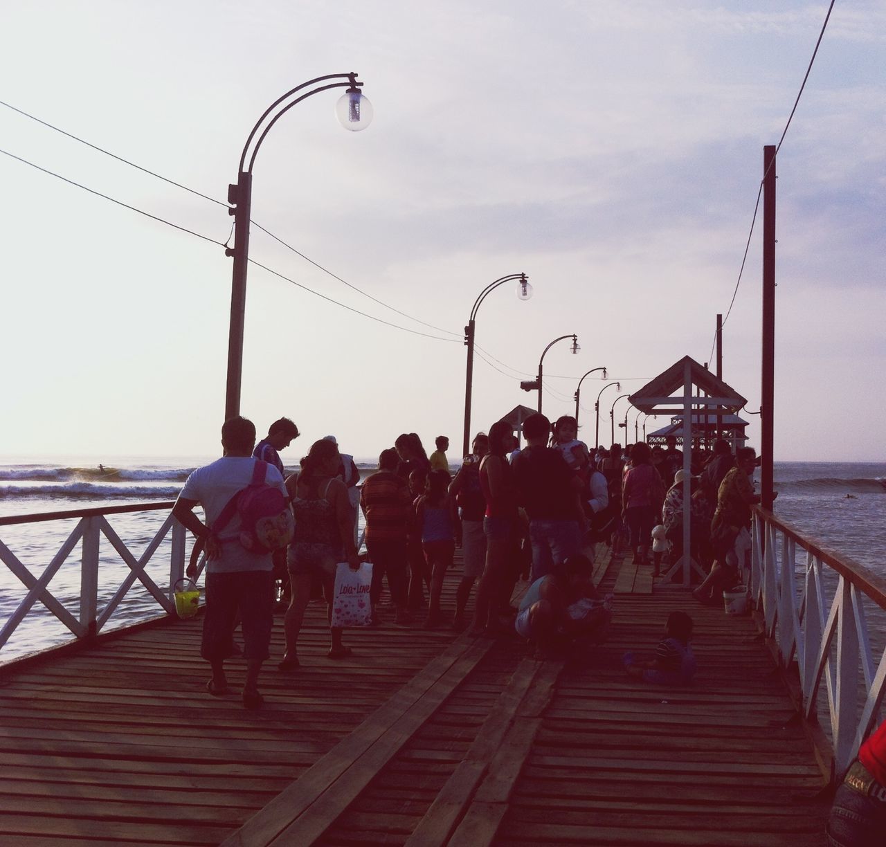 men, lifestyles, railing, leisure activity, water, person, sky, togetherness, full length, pier, rear view, sea, connection, built structure, walking, medium group of people, bonding, the way forward