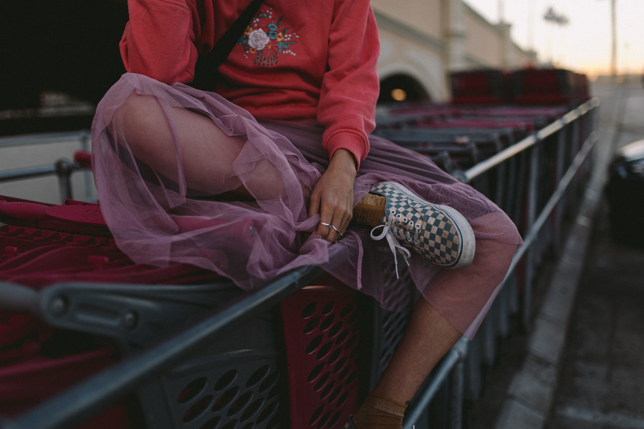 MIDSECTION OF WOMAN HOLDING WHILE SITTING OUTDOORS