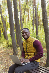 Young woman using laptop while sitting in forest