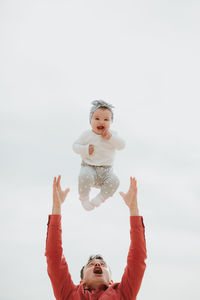 Portrait of smiling boy with arms raised against sky