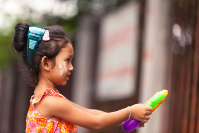 Cute girl holding toy while standing outdoors