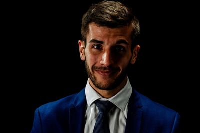 Portrait of young man against black background