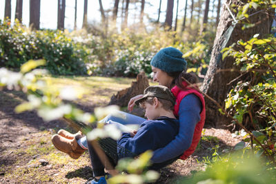 Mother and son sitting on hammock in forest