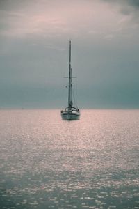 Sailboat sailing on sea against sky during sunset