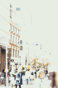 People walking on street in city against clear sky