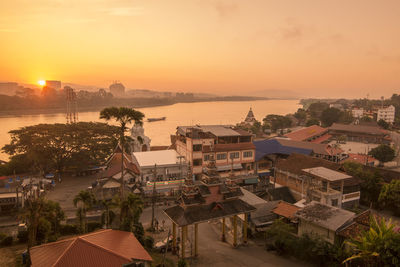 High angle view of townscape by sea during sunset