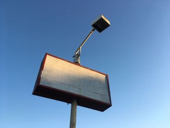 Low angle view of road sign against clear blue sky