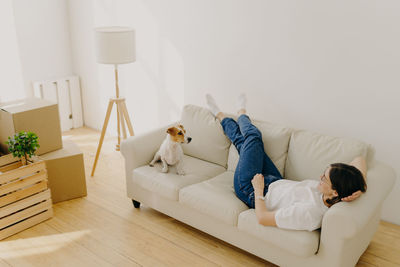 Full length of woman lying on sofa at home