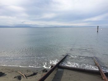 Damaged pier at beach against sky