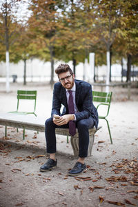 Portrait of smiling businessman sitting at park bench