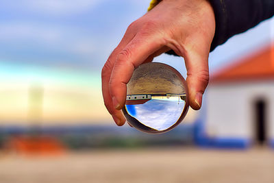 Close-up of person holding umbrella against sky