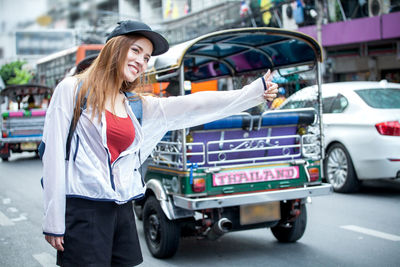 Woman standing by car in city