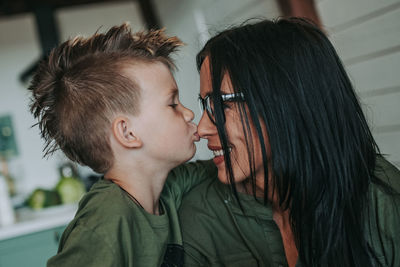 Son kissing mother on nose at home