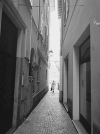 Rear view of people walking on narrow alley amidst buildings