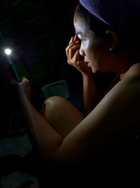 Portrait of young woman sitting in the dark