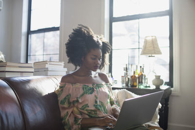 Woman looking away while sitting on window at home