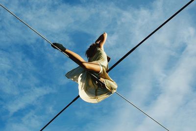 Low angle view of woman on rope against sky