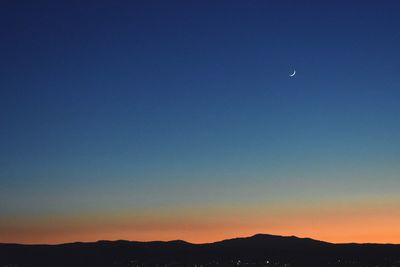 Scenic view of silhouette mountains against clear sky at night