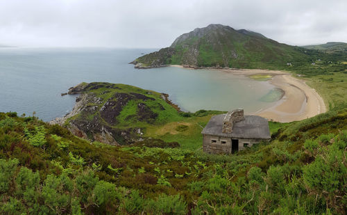 Sandy beach of crummie's bay seen from dunree hill, abandoned stone cottage in foreground