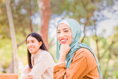 Smiling woman with friend sitting outdoors