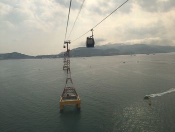 Overhead cable car over sea against sky