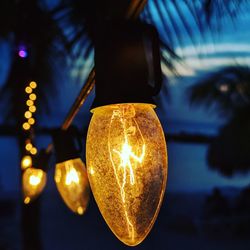 Low angle view of illuminated light bulb hanging from ceiling