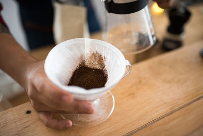 Close-up of hand holding coffee cup on table