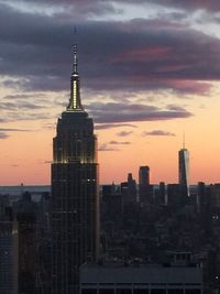 Modern buildings in city against sky during sunset