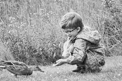 Side view of boy by duck on land