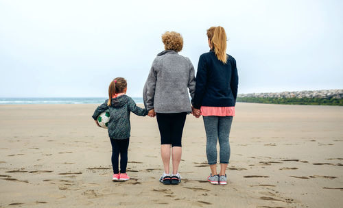 Rear view of family standing at beach