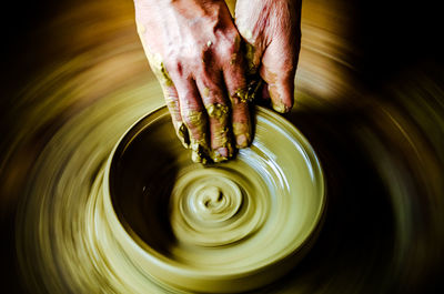 Cropped hand of potter making earthenware at pottery workshop