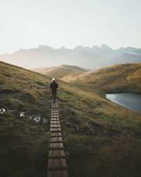 Rear view of man standing on mountain against sky