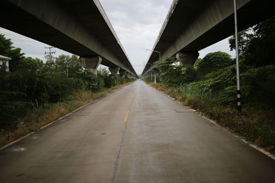 Empty road by bridge against sky